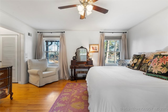 bedroom with crown molding, light hardwood / wood-style floors, and multiple windows