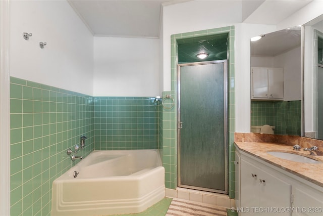 bathroom featuring independent shower and bath, vanity, and tile walls