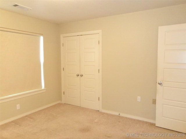 unfurnished bedroom featuring light colored carpet and a closet