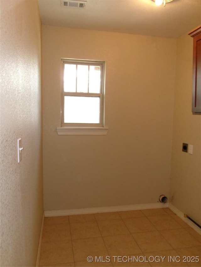 laundry room with electric dryer hookup and light tile patterned floors