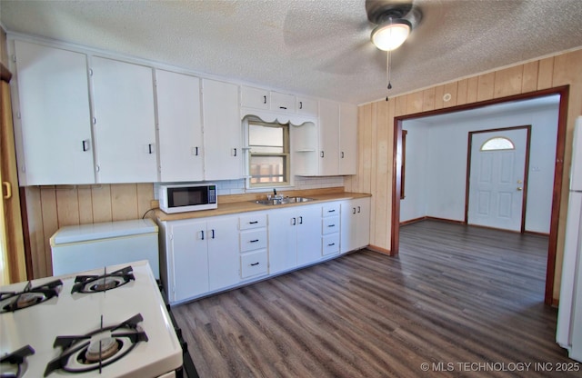 kitchen featuring sink, dark hardwood / wood-style floors, a textured ceiling, white appliances, and white cabinets