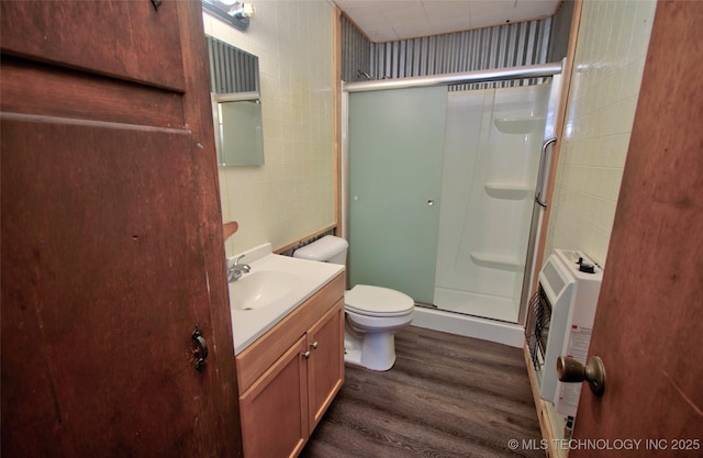 bathroom with vanity, heating unit, a shower with door, hardwood / wood-style floors, and toilet