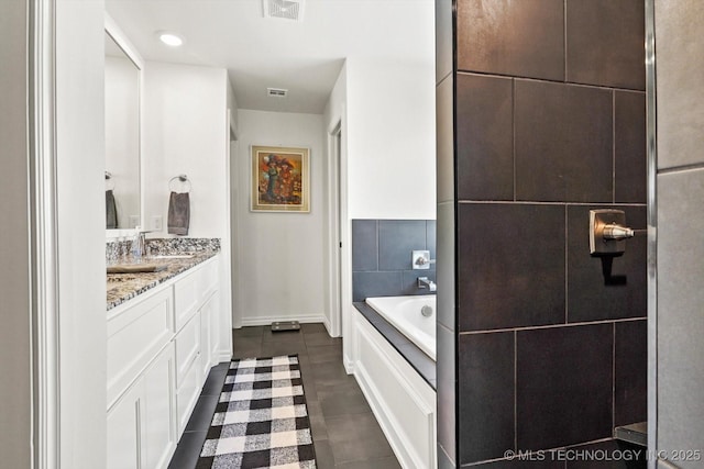 bathroom with a washtub, vanity, and tile patterned floors