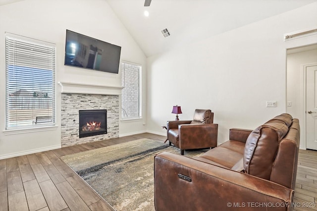 living room featuring ceiling fan, a tile fireplace, hardwood / wood-style floors, and vaulted ceiling