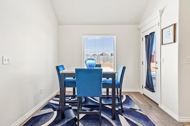 dining space featuring hardwood / wood-style floors and vaulted ceiling