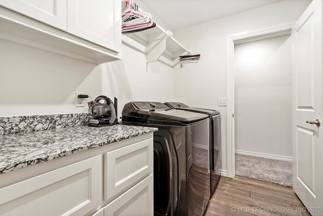 clothes washing area with washer and dryer, cabinets, and light wood-type flooring