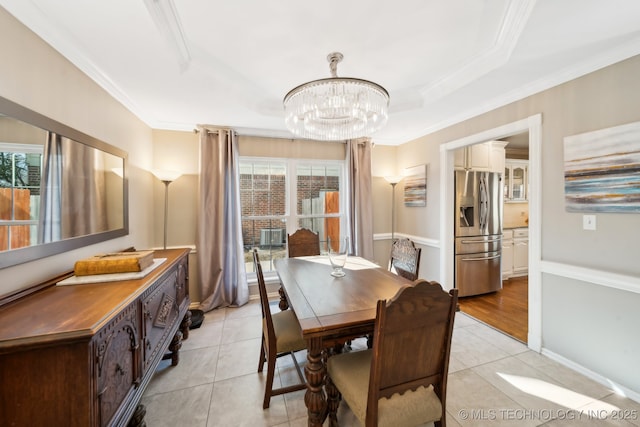 dining area with a tray ceiling, crown molding, a chandelier, and light tile patterned floors