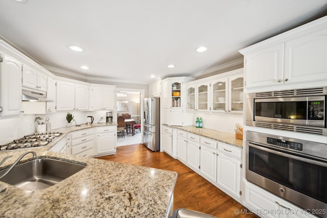 kitchen with appliances with stainless steel finishes, white cabinets, sink, and light stone countertops