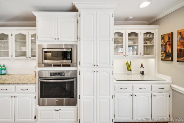 kitchen with appliances with stainless steel finishes, ornamental molding, and white cabinetry