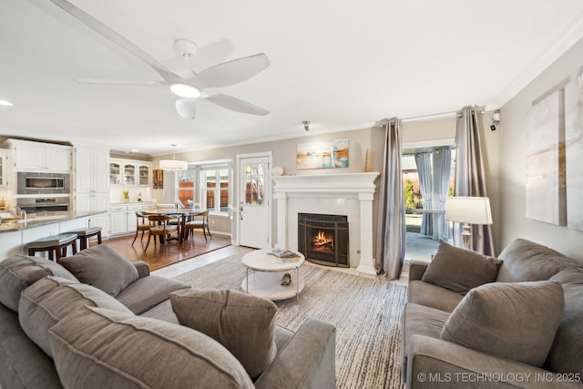 living room featuring ceiling fan, light hardwood / wood-style floors, and crown molding