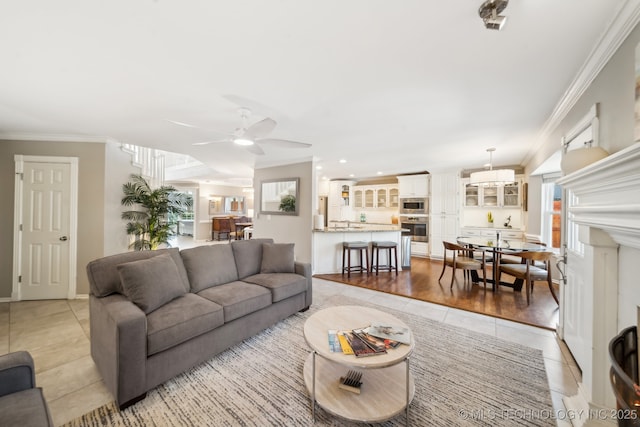 living room featuring sink, ceiling fan, light tile patterned floors, and crown molding