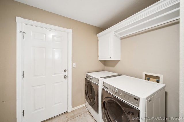 washroom featuring light tile patterned flooring, cabinets, and washing machine and clothes dryer