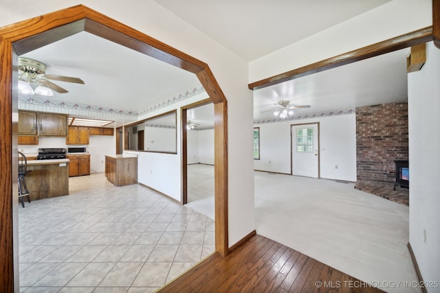 interior space with ceiling fan, a wood stove, and light wood-type flooring