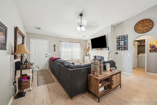 living room featuring light hardwood / wood-style floors, ceiling fan, and washer / dryer