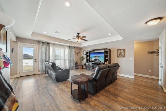 living room with wood-type flooring, ceiling fan, and a tray ceiling