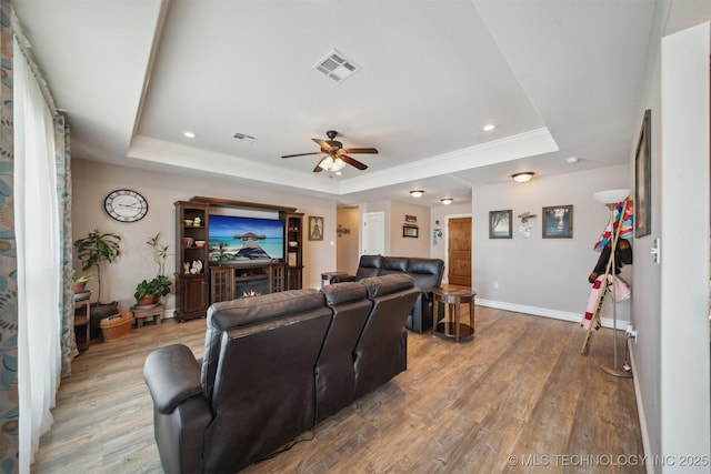 living room with hardwood / wood-style flooring, ceiling fan, and a tray ceiling