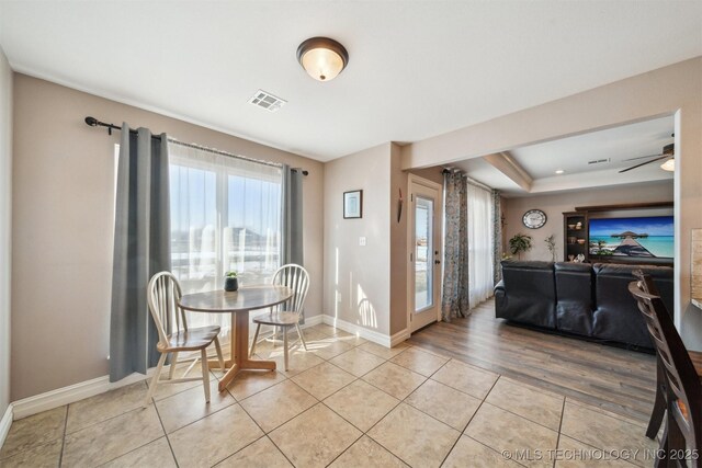 tiled dining room featuring a raised ceiling and ceiling fan