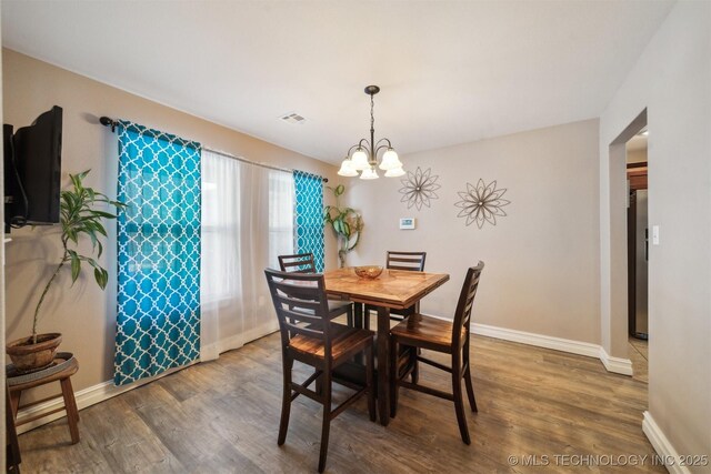 dining room with dark hardwood / wood-style flooring and an inviting chandelier