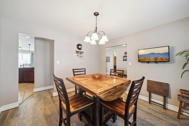 dining space featuring hardwood / wood-style flooring and an inviting chandelier