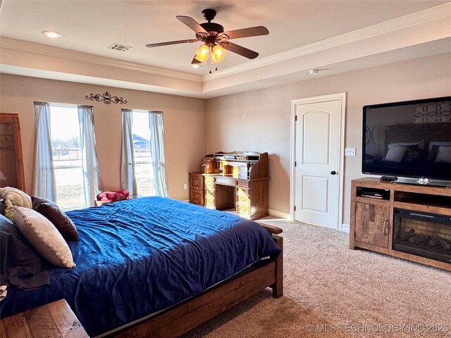 carpeted bedroom with ceiling fan, a tray ceiling, and ornamental molding