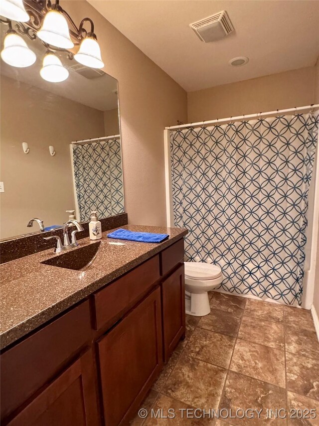 bathroom with toilet, a notable chandelier, and vanity