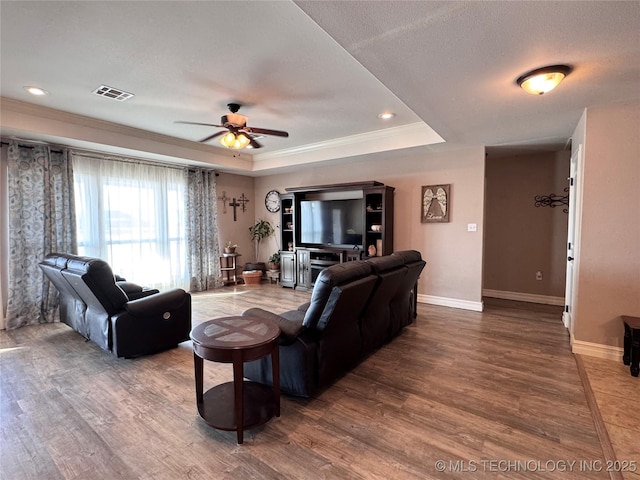 living room featuring ceiling fan, hardwood / wood-style floors, crown molding, and a tray ceiling