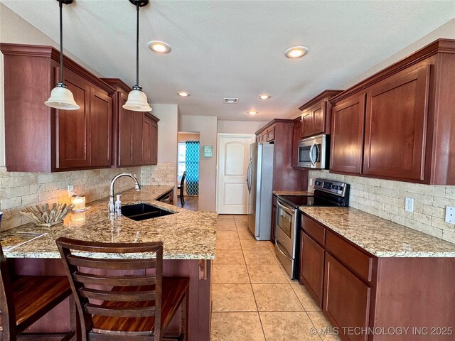 kitchen featuring a kitchen breakfast bar, stainless steel appliances, hanging light fixtures, kitchen peninsula, and sink