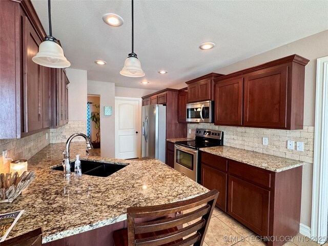 kitchen featuring sink, hanging light fixtures, kitchen peninsula, and appliances with stainless steel finishes