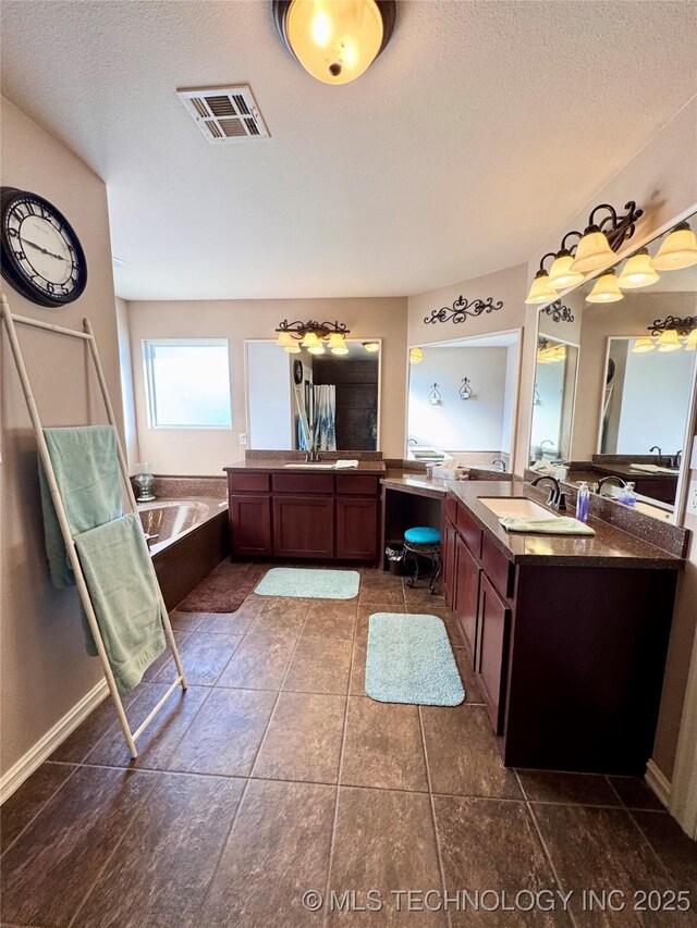 bathroom with tile patterned flooring, a textured ceiling, a tub to relax in, and vanity