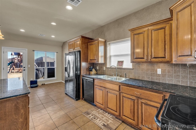 kitchen featuring sink, light tile patterned flooring, decorative backsplash, dark stone counters, and black appliances