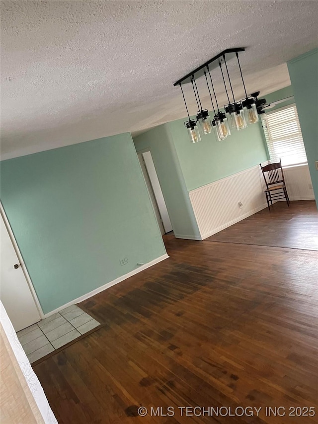 empty room with dark hardwood / wood-style flooring and a textured ceiling