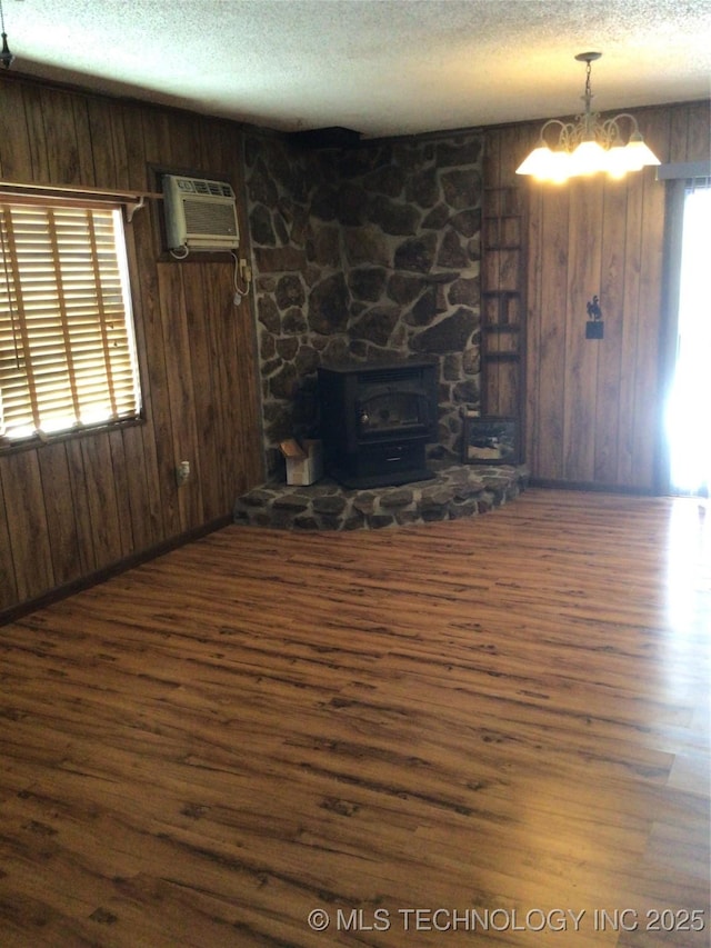 unfurnished living room featuring dark hardwood / wood-style flooring, an AC wall unit, wooden walls, and a wood stove