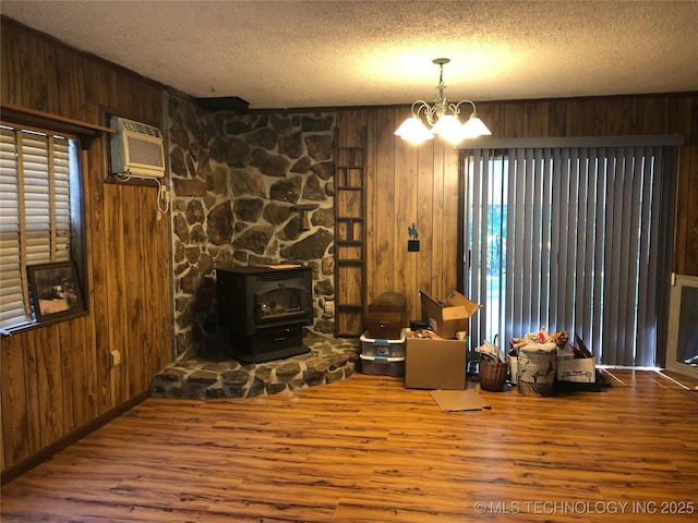 living room with wood walls, a chandelier, a wall mounted air conditioner, hardwood / wood-style flooring, and a textured ceiling