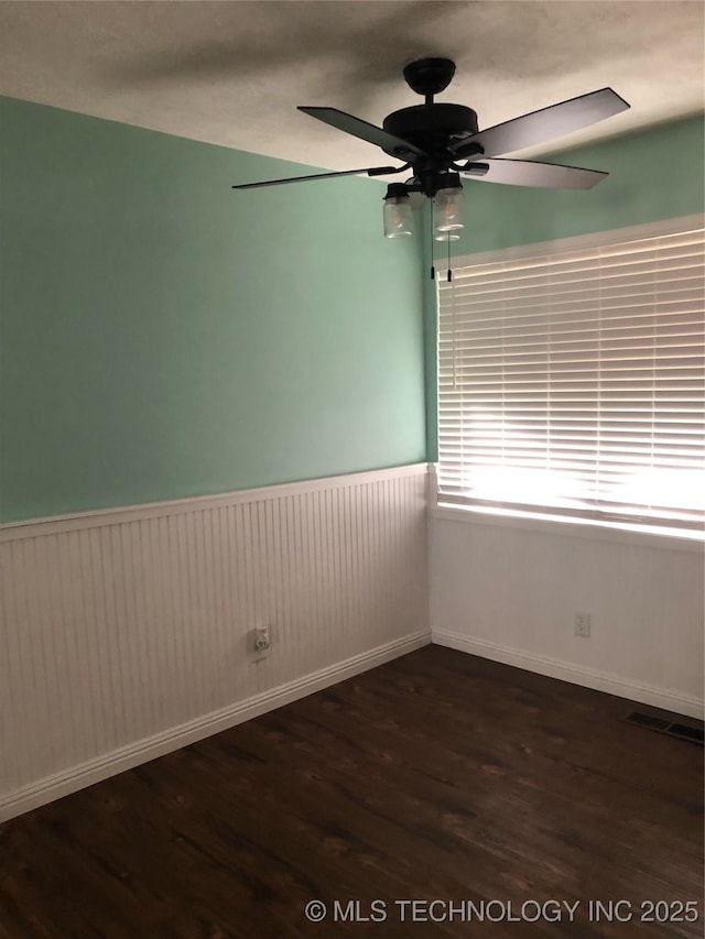 empty room featuring dark wood-type flooring and ceiling fan