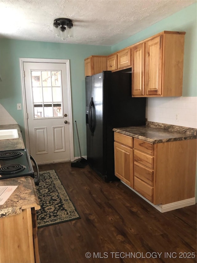 kitchen with black fridge, a textured ceiling, and dark hardwood / wood-style floors