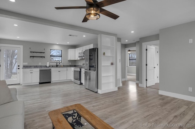 kitchen featuring ceiling fan, sink, light wood-type flooring, stainless steel appliances, and white cabinets