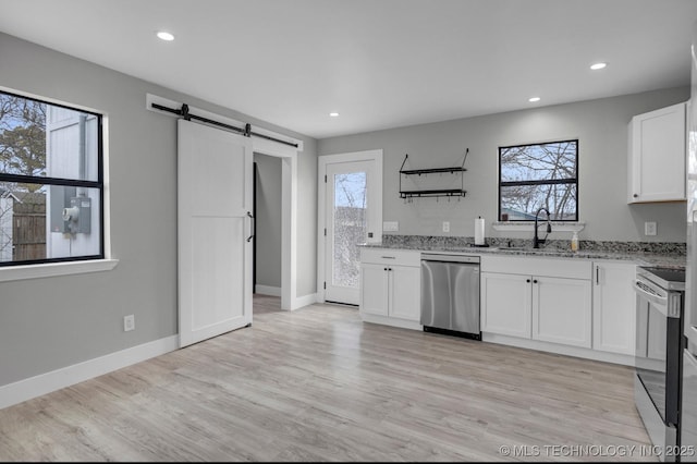 kitchen featuring a barn door, sink, white cabinetry, light stone countertops, and appliances with stainless steel finishes