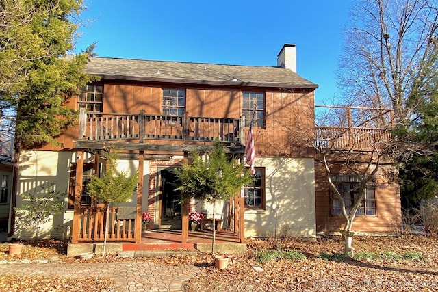 back of house featuring a patio area, a chimney, and roof with shingles