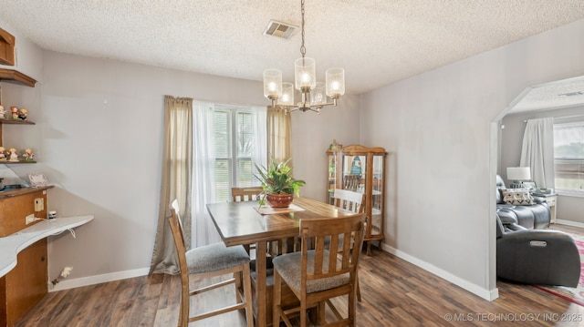 2019 Mckenzie Rd, Pawhuska, OK 74056 - dining area featuring dark wood finished floors, a textured ceiling, plenty of natural light, and a chandelier