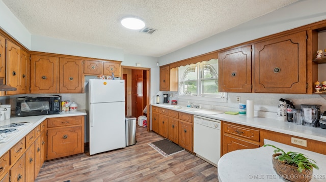 2019 Mckenzie Rd, Pawhuska, OK 74056 - kitchen with white appliances, a textured ceiling, and brown cabinetry