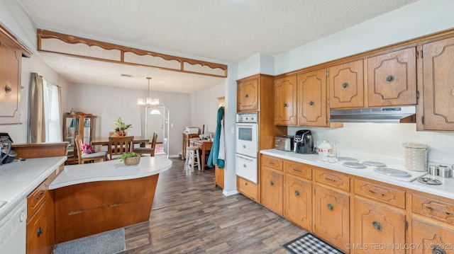 2019 Mckenzie Rd, Pawhuska, OK 74056 - kitchen with under cabinet range hood, white appliances, brown cabinets, a textured ceiling, and light countertops