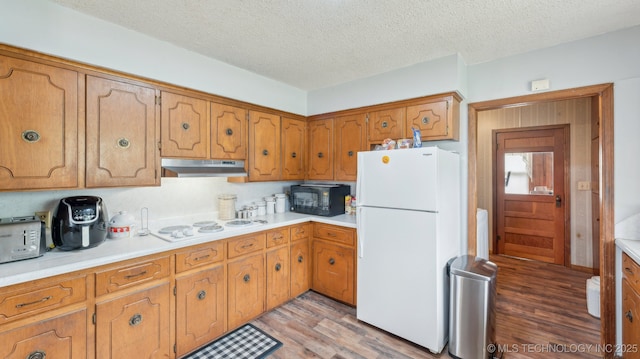 2019 Mckenzie Rd, Pawhuska, OK 74056 - kitchen featuring white appliances, under cabinet range hood, light wood finished floors, a textured ceiling, and light countertops
