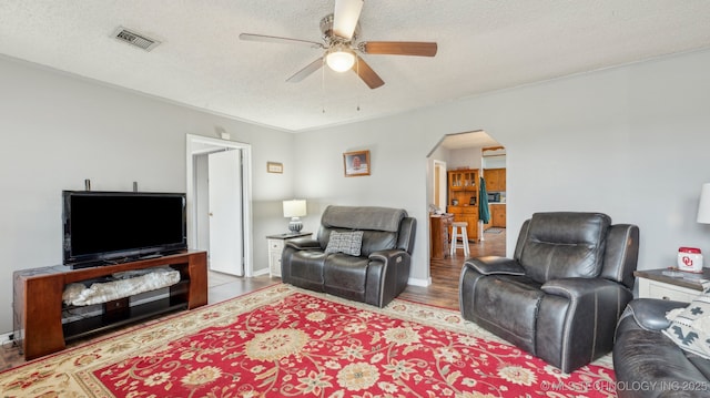 2019 Mckenzie Rd, Pawhuska, OK 74056 - living room featuring arched walkways, ceiling fan, a textured ceiling, ornamental molding, and wood finished floors