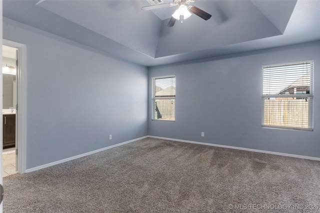 empty room featuring ceiling fan, light colored carpet, and a raised ceiling