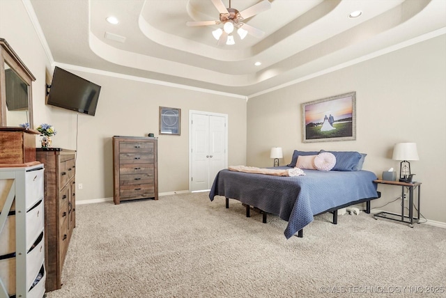 bedroom with a raised ceiling, a closet, ceiling fan, ornamental molding, and light carpet