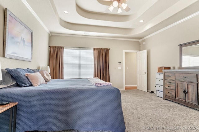 carpeted bedroom with a raised ceiling, ceiling fan, and crown molding