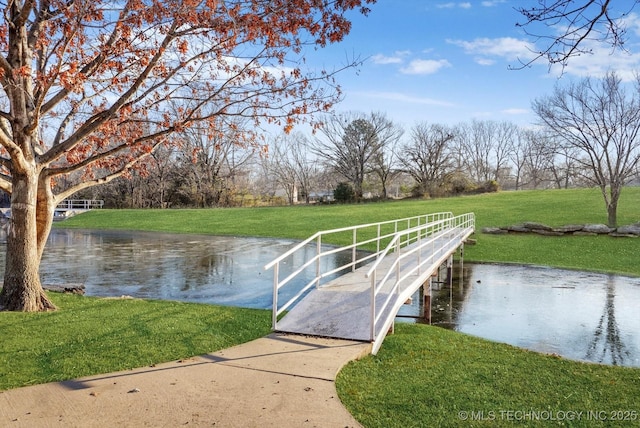 view of dock with a yard and a water view