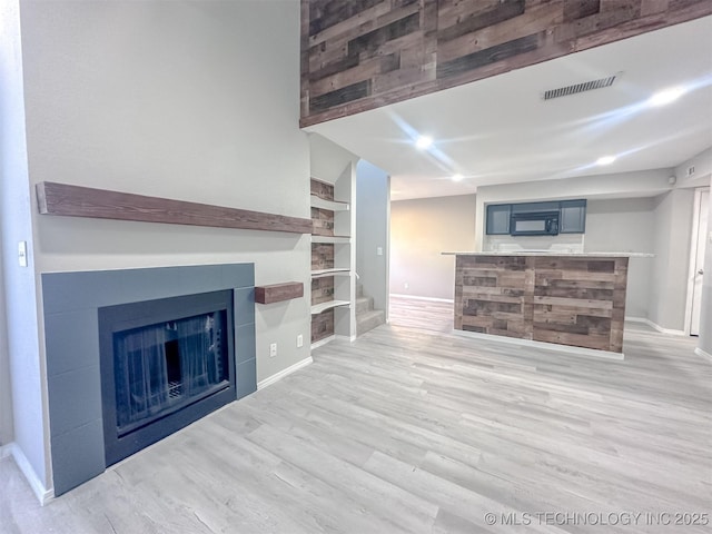 unfurnished living room featuring light wood-type flooring and built in features