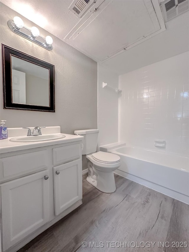 full bathroom with toilet, hardwood / wood-style flooring, a textured ceiling,  shower combination, and vanity