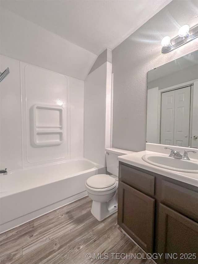 full bathroom with bathing tub / shower combination, toilet, vanity, and wood-type flooring